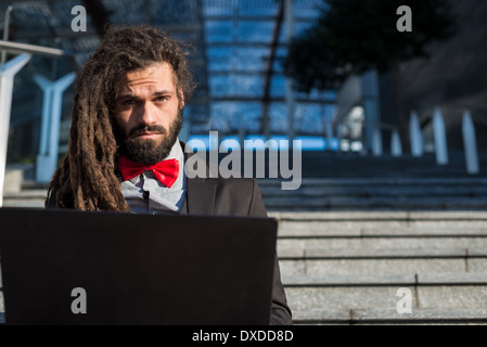 Stylish elegant dreadlocks businessman using notebook in business landscape Stock Photo
