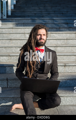 Stylish elegant dreadlocks businessman using notebook in business landscape Stock Photo