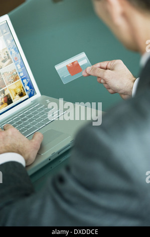 Businessman holding credit card at laptop Stock Photo