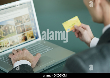 Businessman holding credit card at laptop Stock Photo