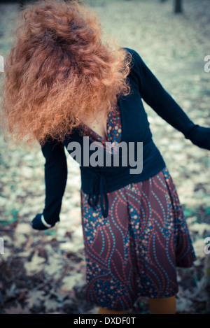 young beautiful red curly hair woman at the park