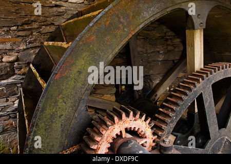 Enclosed water mill wheel workings with ancient metal and wooden cog system part of industrial heritage. Stock Photo