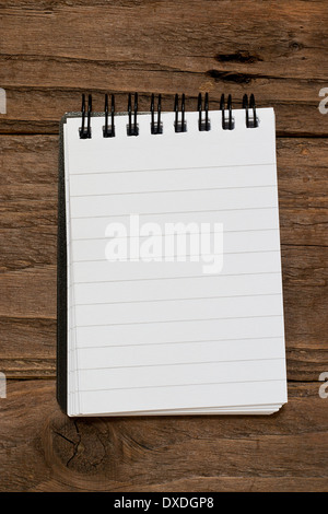 Small pocket sized notepad on a rustic wooden background with blank space for inserting your own message or note. Stock Photo