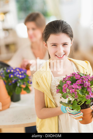 Girl (8-9) and mother potting flowers Stock Photo