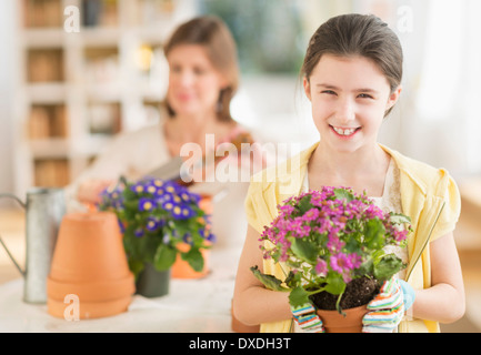 Girl (8-9) and mother potting flowers Stock Photo