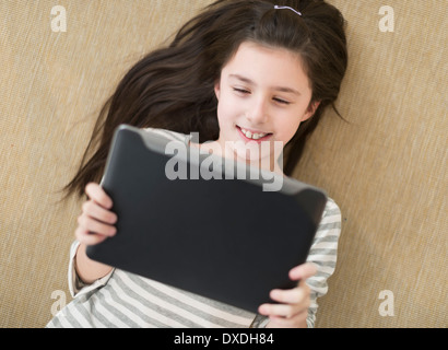 Girl (8-9) lying on floor using tablet pc Stock Photo