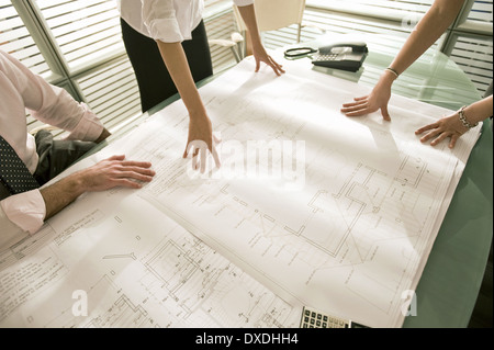 Closeup of professionals looking at architectural plans on desk Stock Photo