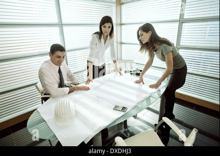 Professionals looking at architectural plans on desk Stock Photo