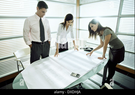 Professionals looking at architectural plans on desk Stock Photo