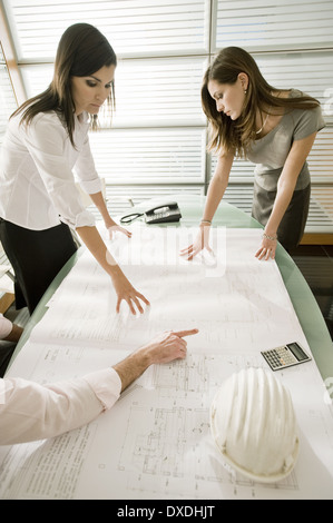 Professionals looking at architectural plans on desk Stock Photo