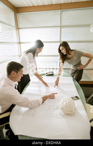 Professionals looking at architectural plans on desk Stock Photo