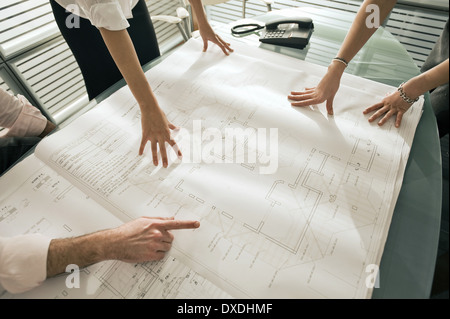 Closeup of professionals looking at architectural plans on desk Stock Photo