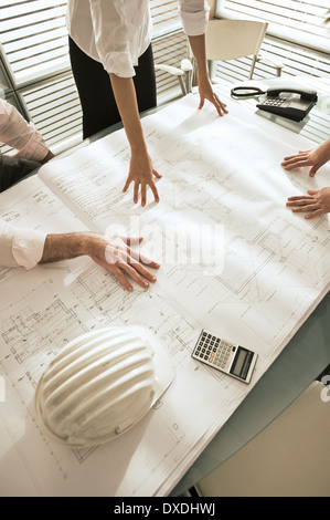 Closeup of professionals looking at architectural plans on desk Stock Photo