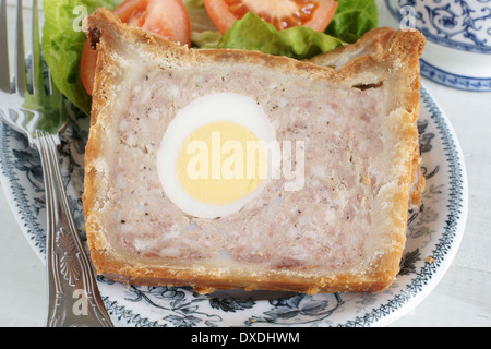 Pork and egg gala pie with salad, pickle and salad cream on a wooden ...