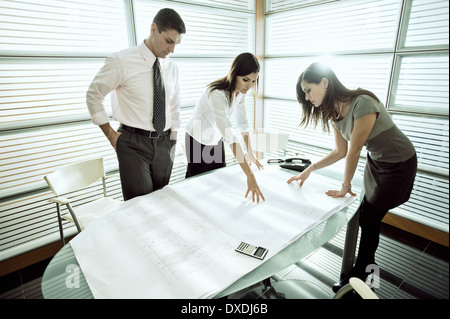 Professionals looking at architectural plans on desk Stock Photo