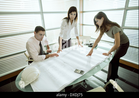 Professionals looking at architectural plans on desk Stock Photo