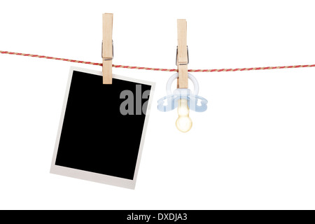 Instant photo and pacifier hanging on the clothesline. Isolated on white background Stock Photo