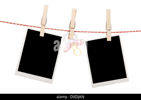 Instant photo frames and pacifier hanging on the clothesline. Isolated on white background Stock Photo