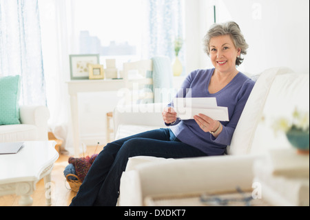 Woman sitting on coach reading letters Stock Photo