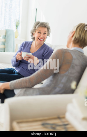 Two women sitting on coach talking Stock Photo