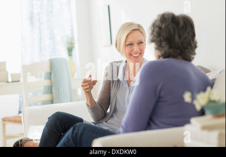 Two women sitting on coach talking Stock Photo