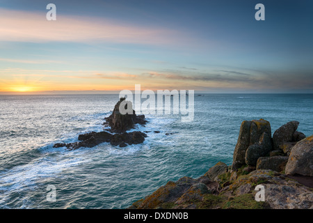 Rocky cliffs and sea stacks at Lands End in Cornwall with the Longships lighthouse in the distance Stock Photo