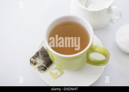 Used Tea Bag on Saucer with Cup of Tea in Green Mug with Sugar Bowl, Studio Shot Stock Photo