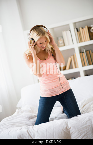 Young woman listening to music in bedroom Stock Photo