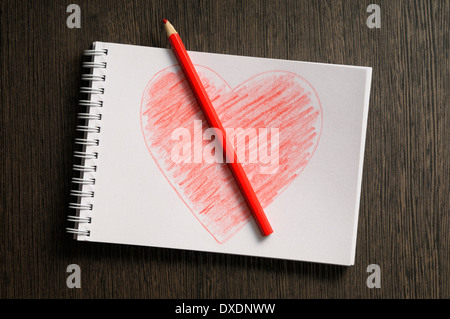 heart shaped drawing on notebook and colored pencil, wooden background, studio shot Stock Photo