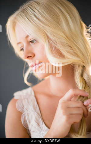 Portrait of young woman braiding hair Stock Photo