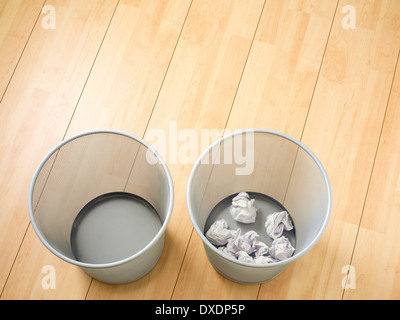Overhead view of empty and used waste baskets on wooden floor, studio shot Stock Photo