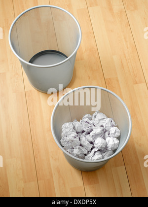 Overhead view of empty and used waste baskets on wooden floor, studio shot Stock Photo