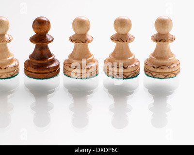 Dark wooden chess piece in row of light wooden chess pieces Stock Photo