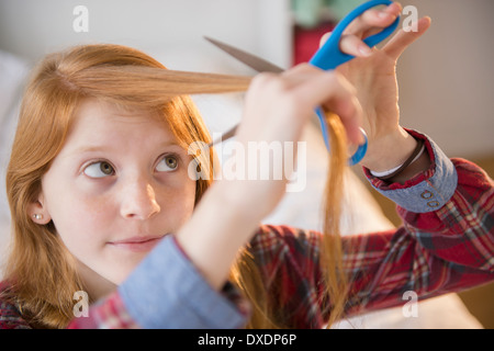 Portrait of girl (12-13) cutting her hair Stock Photo