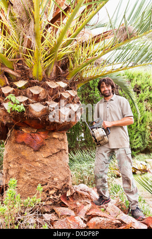 Portrait of man holding chainsaw for peeling palm tree, Majorca, Spain Stock Photo