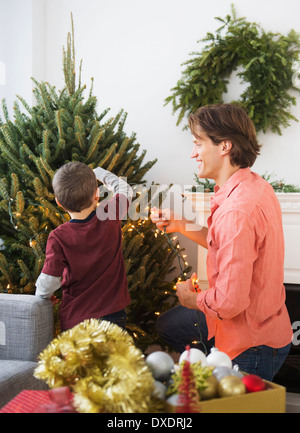Man with kid (6-7) decorating Christmas tree Stock Photo