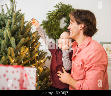 Man with kid (6-7) decorating Christmas tree Stock Photo