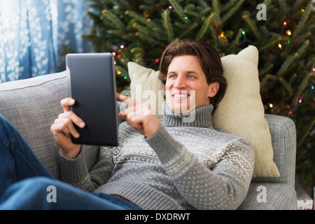 Man lying on sofa and using tablet Stock Photo