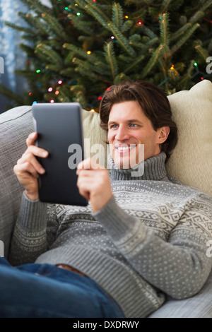 Man lying on sofa and using tablet Stock Photo