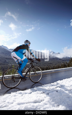 Man riding bike in winter mountains, British Columbia, Canada Stock Photo