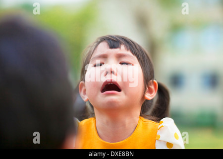 little asian girl crying and look at  her parents in the park Stock Photo