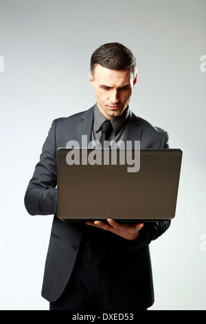 Confident businessman using laptop on gray background Stock Photo