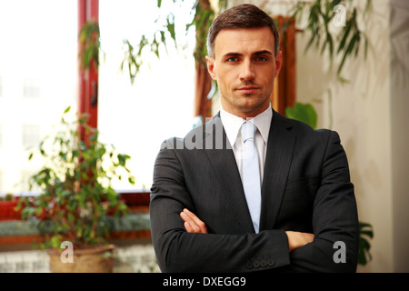 Confident businessman standing with arms folded at office Stock Photo