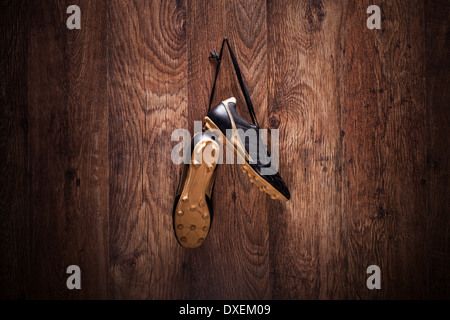 Pair of football boots hanging on a wooden wall Stock Photo