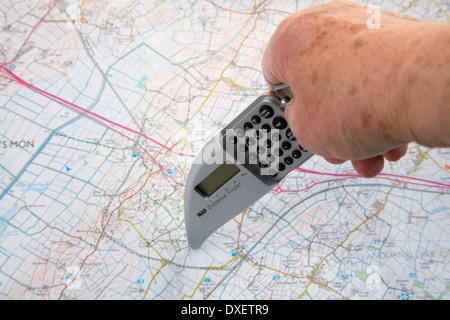 Close up woman's hand holding distance finder measuring tool on an ordnance survey map Stock Photo