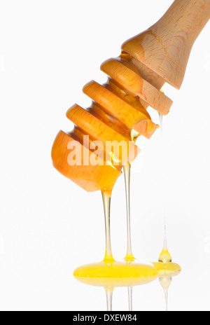 Honey dripping from a wooden honey dipper Stock Photo