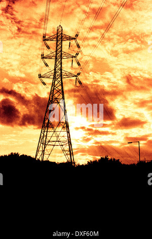 Electrical transmission tower over dramatic sunset sky. Toned grainy 35mm film scan. Stock Photo