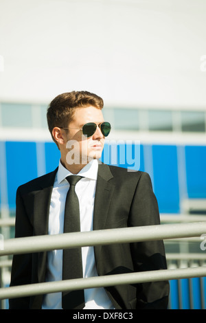Young businessman wearing sunglasses, standing outdoors, Germany Stock Photo