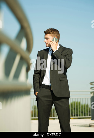 Portrait of businessman standing by railing and using cell phone, Germany Stock Photo