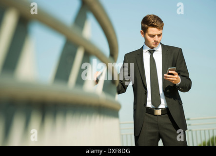 Portrait of businessman standing by railing and looking at smartphone, Germany Stock Photo